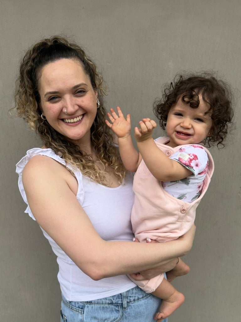 Mujer con su hija pequeña, ambas con cabello castaño rizado, posando juntas